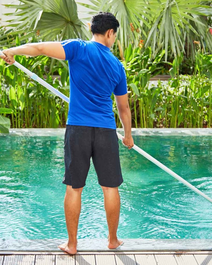 YOUNG MAN CLEANING A POOL